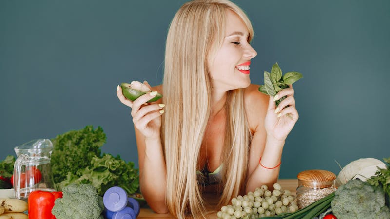 Woman surrounded by colorful whole foods planning an elimination diet