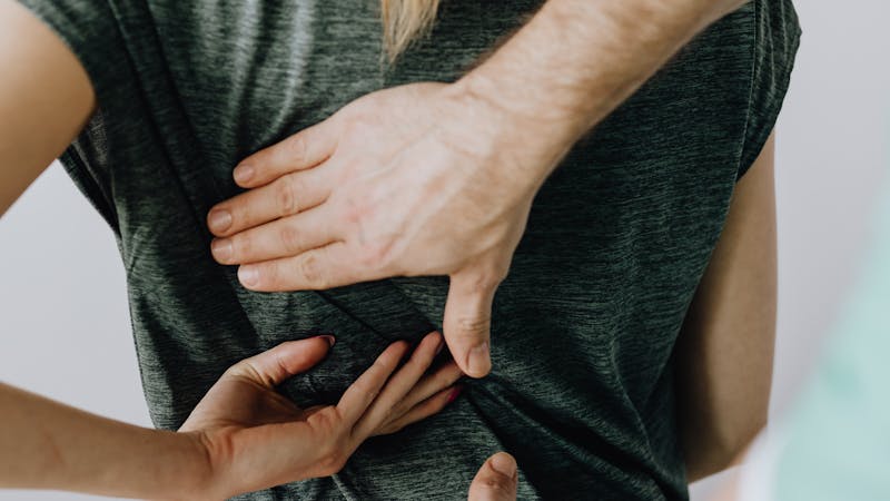 Chiropractor examining patient's lower back in clinic