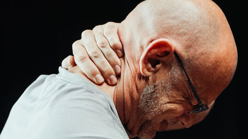 Man holding the back of his neck in pain from spinal nerve interference