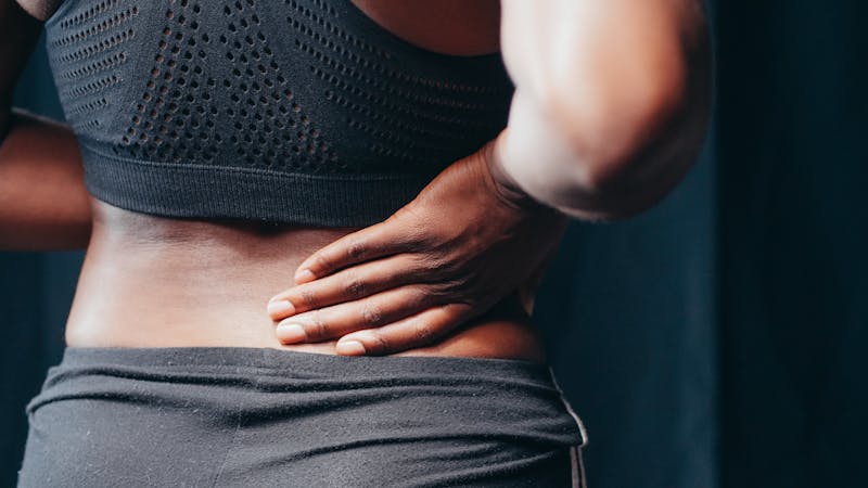 Woman holding her lower back and hip in pain from pelvic misalignment