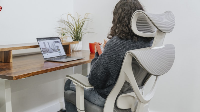 Woman sitting in ergonomic office chair working at desk with laptop