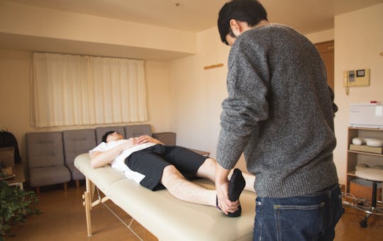 Therapist applying shockwave treatment to patient on treatment table